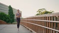 Motivated athlete running morning bridge. Woman doing cardio training jogging