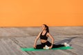 Motivated athletic positive woman in tight sportswear, black pants and top, practicing yoga, doing one legged king pigeon pose Royalty Free Stock Photo