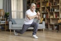 Motivated athletic senior man doing lunges at home