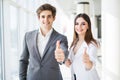 Motivated businessman and woman giving a thumbs up gesture of approval and success as they pose side by side giving the camera big Royalty Free Stock Photo