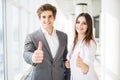 Motivated businessman and woman giving a thumbs up gesture of approval and success as they pose side by side giving the camera big Royalty Free Stock Photo