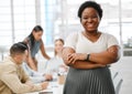 Motivated, confident and happy female leader standing with her arms crossed in the boardroom with colleagues in the