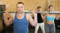 Motivated CrossFit middle-aged male athlete lifting heavy body bar or barbell during group training in gym. Functional Royalty Free Stock Photo