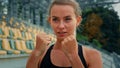 Motivated female fighter athlete with clenched fists standing in boxing stance punching air dynamic arms blows training