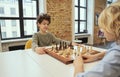 Motivated little boy sitting in the classroom and planning a move while playing chess on the chessboard with his friend Royalty Free Stock Photo