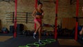 Sporty fit black woman practicing high knee walking exercise with agility ladder