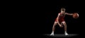 Full-length studio shot of boy, basketball player in motion, dribbling ball isolated over black background. Flyer Royalty Free Stock Photo