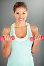 Motivated to reach her fitness goals. a young woman working out with dumbbells against a gray background. Royalty Free Stock Photo