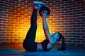 Motivated young brunette woman exercise for abs with medicine ball on the fitness mat in gym in neon lights. Royalty Free Stock Photo