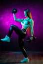 Motivated young woman fitness model workout with professional dumbbells in neon lights in the studio. Royalty Free Stock Photo