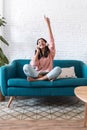 Motivated young woman listening to music with digital tablet while sitting on sofa at home