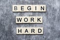 The motivating slogan Begin Work Harder formed with tile letters