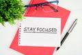 Motivation concept. STAY FOCUSED written on a piece of paper on a red notebook on a white background Royalty Free Stock Photo