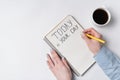 Motivational inscription TODAY IS YOUR DAY. Top view of woman writing in Notepad. Morning coffee