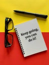 Motivational and inspirational concept - Keep going, you can do it. With glasses, pen, yellow and red background Royalty Free Stock Photo