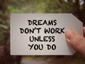 Motivational and inspirational wording. Dreams Don& x27;t Work Unless You Do written on a paper. With blurred styled back.
