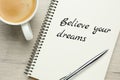 Motivational quote Believe Your Dreams written in notebook on wooden table, flat lay Royalty Free Stock Photo