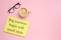 Motivational quote Big journeys begin with small steps, cup of coffee and glasses on pink background, flat lay. Space for text Royalty Free Stock Photo