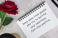 Motivational quote on a note book with roses on a desk.