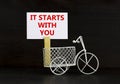 Motivational, start symbol. Wooden clothespin, white sheet of paper. Words `it starts with you`. Miniature bicycle model. Royalty Free Stock Photo