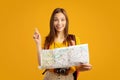 Motiveted young woman tourist holding city map, showing eureka gesture