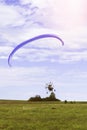 Moto paraglider flying over a field in a blue sky with clouds. Royalty Free Stock Photo