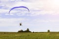 Moto paraglider flying over a field in a blue sky with clouds. Royalty Free Stock Photo