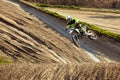 Motocross driver in action accelerating the motorbike takes off and jumps on springboard on the race track. Royalty Free Stock Photo