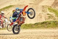 Motocross driver in action accelerating the motorbike takes off and jumps on springboard on the race track. Royalty Free Stock Photo