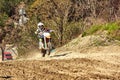 Motocross driver in action accelerating the motorbike takes off and jumps on springboard on the race track. Royalty Free Stock Photo