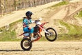 Motocross driver in action accelerating the motorbike takes off and jumps on springboard on the race track. Royalty Free Stock Photo