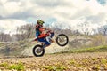 Motocross driver in action accelerating the motorbike takes off and jumps on springboard on the race track. Royalty Free Stock Photo