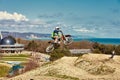 Motocross driver in action accelerating the motorbike takes off and jumps on springboard on the race track. Royalty Free Stock Photo