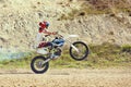 Motocross driver in action accelerating the motorbike takes off and jumps on springboard on the race track. Royalty Free Stock Photo