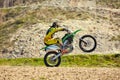 Motocross driver in action accelerating the motorbike takes off and jumps on springboard on the race track. Royalty Free Stock Photo