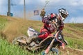 Motocross. Motorcyclist rushes along a dirt road, dirt flies from under the wheels. Green vegetation and blue sky.