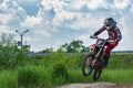 Motocross. Motorcyclist rushes along a dirt road. Greenery in the foreground.