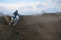 Motocross racer moves along sandy parapet turning track Royalty Free Stock Photo