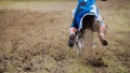 Motocross racer start riding his dirt Cross MX bike kicking up dust rear view, close up Royalty Free Stock Photo