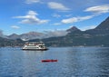 The Motonave Traghetto Plinio approaching Varenna from Lake Como with a red kayak in moored in the foreground.