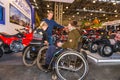 Motopark-2015 (BikePark-2015). Young couple visitors in wheelchairs looking exhibition stand with motorcycles and ATVs. Royalty Free Stock Photo