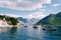 Motor boats are moored off the coast of Perast against the backdrop of ancient houses at the foot of the mountains