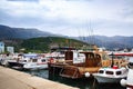 Motor boats and sailboats docked in harbor against mountains. Fishing boats at pier in cloudy day. Royalty Free Stock Photo