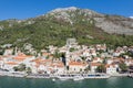 Motor boats stand off the coast of Perast against the backdrop of the Church of St. Nicholas and ancient houses