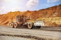 Motor grader levels the ground on background of sandy quarry