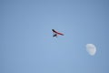 Motor hang glider flying free in the daytime sky with the moon