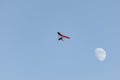 Motor hang glider flying free in the daytime sky with the moon