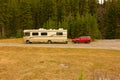 A motor home towing a car through alberta in the springtime