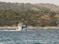 Motor yacht running along the blue sea along the shore. Adriatic sea of Mediterranean area. Dalmatian region of Croatian country. Royalty Free Stock Photo