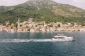 Motor yacht sails the sea along the coast of an ancient town. Perast, Montenegro. Drone